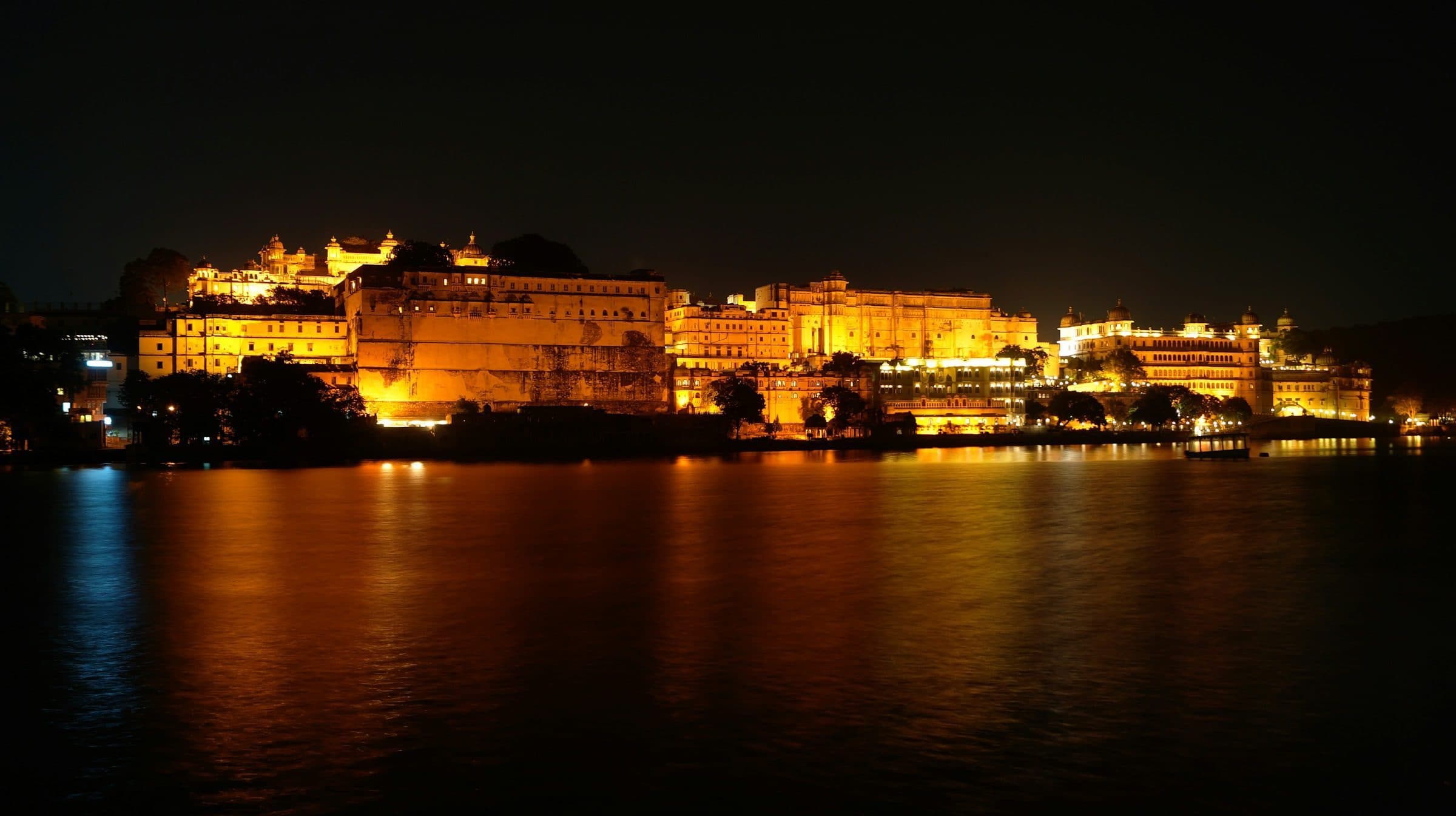 City Palace in Udaipur floodlit at night and reflected in Lake Pichola