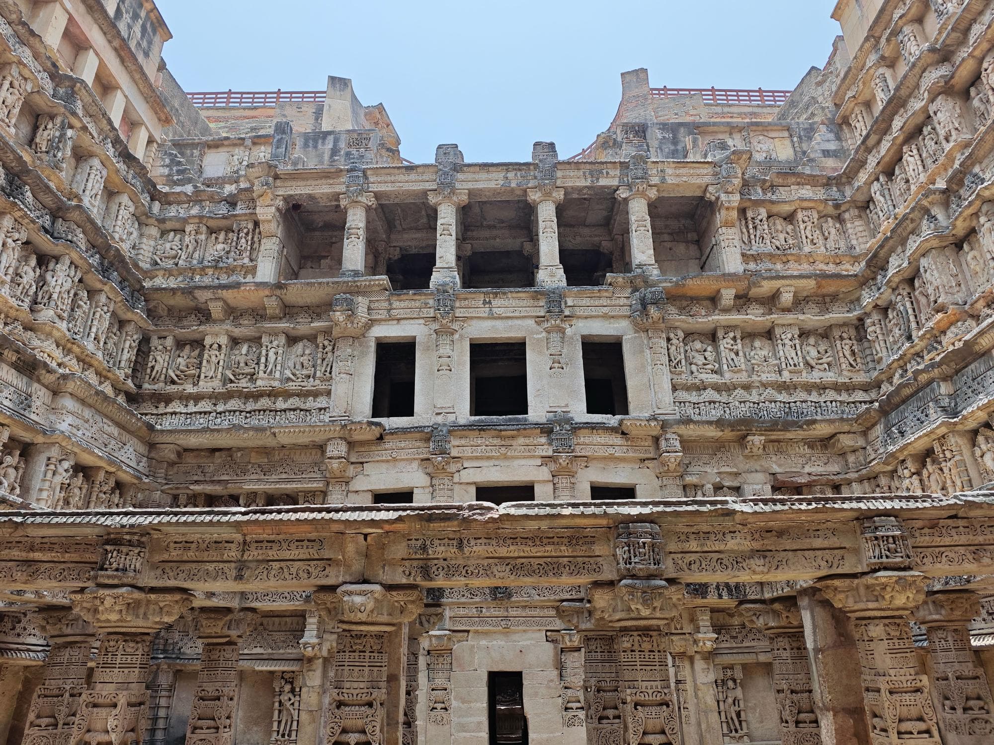 Low-angle view inside the Rani ki Vav stepwell in Patan, Gujarat, showing tiers of carved stone galleries and sculpted deity panels
